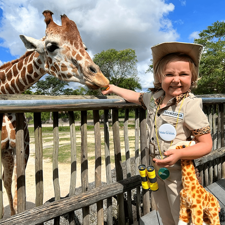 Wish Kid Amelia feeding a giraffe.