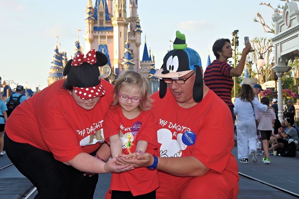 Wish Kid Aubrey and her parents holding virtual Tinkerbell in front of Cinderella's castle at Disney World