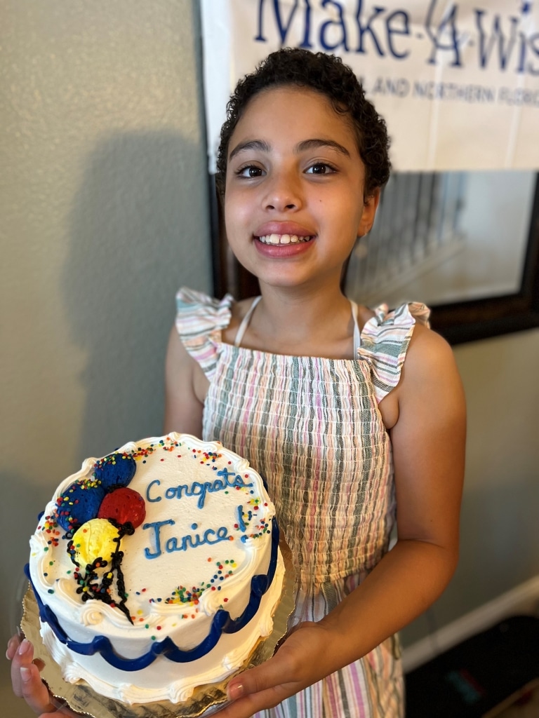 Wish kid Janice holding a cake at her wish reveal